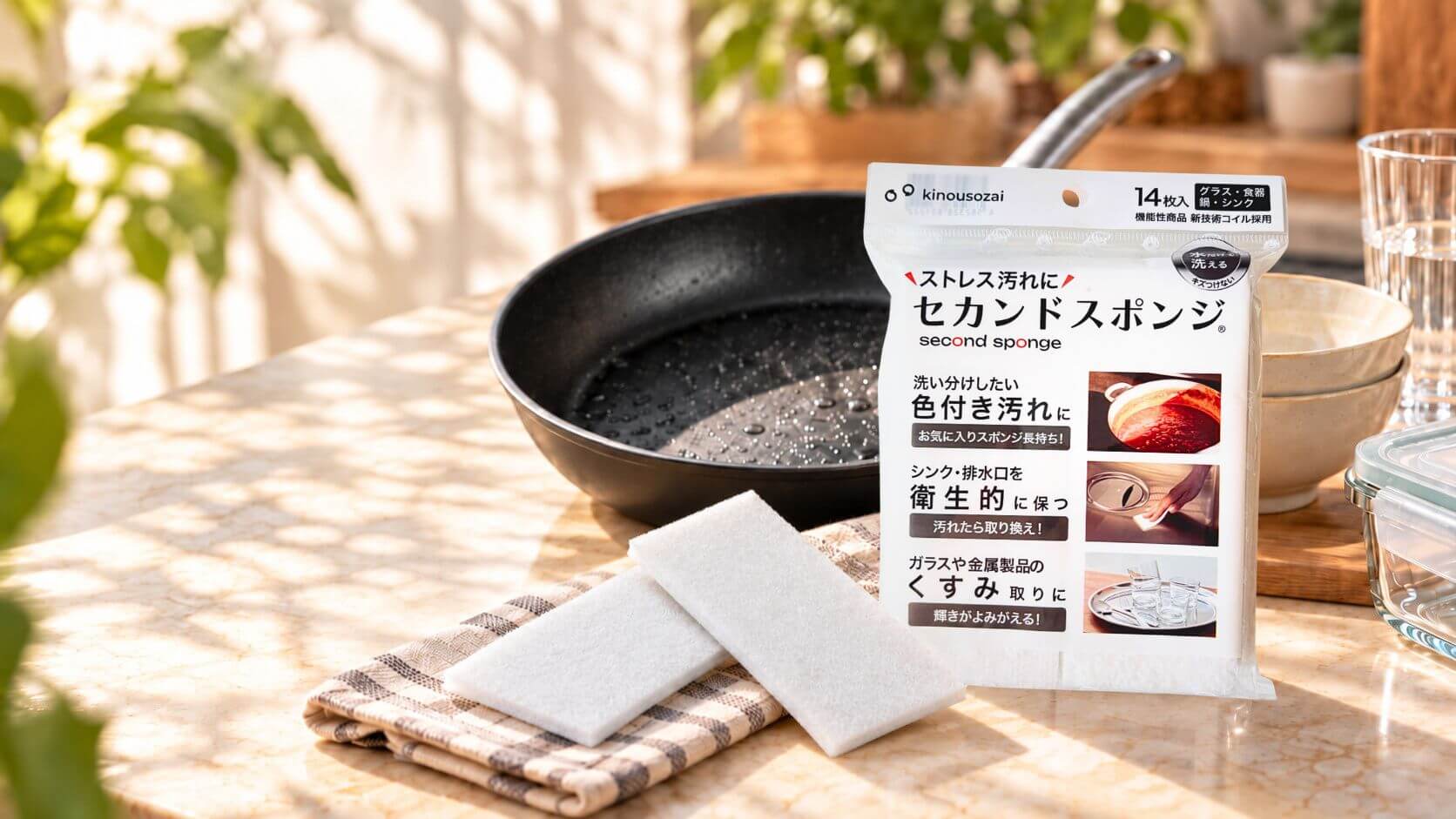Second Sponge 14 入包裝、兩片纖薄菜瓜布、不沾鍋、瓷器碗、玻璃杯與保鮮盒置於廚房檯面